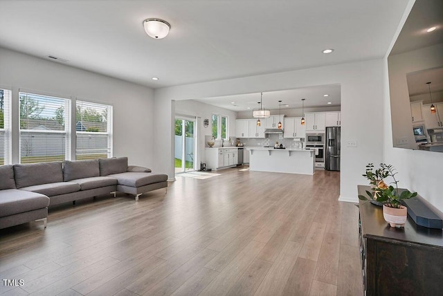 living area featuring light wood-type flooring and recessed lighting