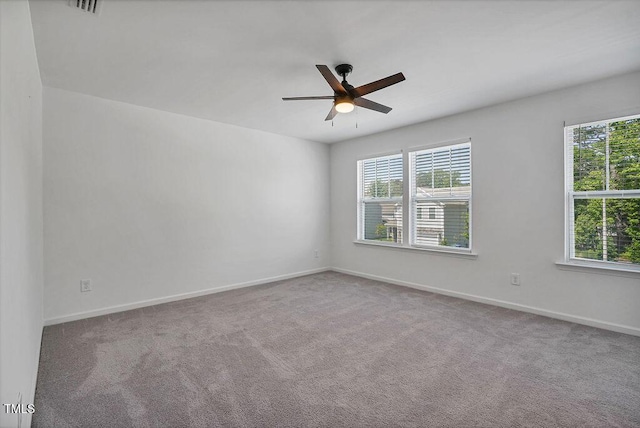 empty room featuring plenty of natural light, a ceiling fan, carpet, and baseboards