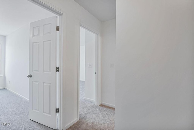 hallway featuring carpet flooring and baseboards