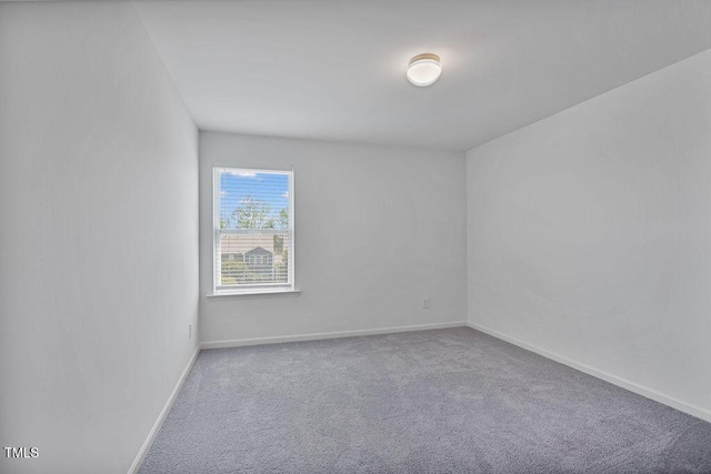 carpeted spare room featuring baseboards