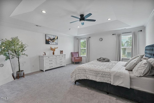 bedroom with a tray ceiling, multiple windows, carpet, crown molding, and recessed lighting