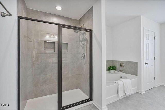 bathroom with a shower stall, a garden tub, baseboards, and tile patterned floors