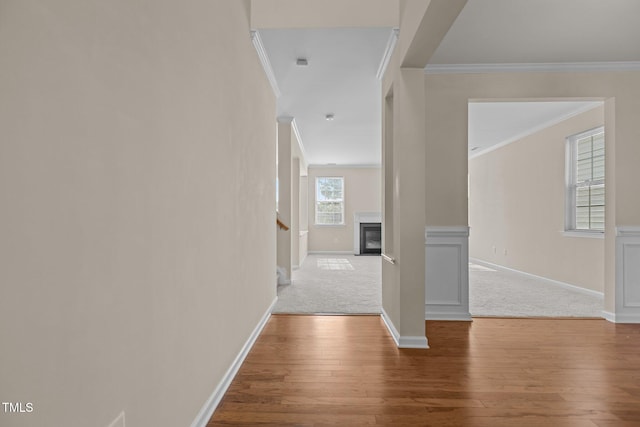 hall featuring wood-type flooring, ornamental molding, baseboards, and stairway