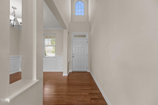 doorway to outside with an inviting chandelier, crown molding, dark wood-style floors, and a healthy amount of sunlight