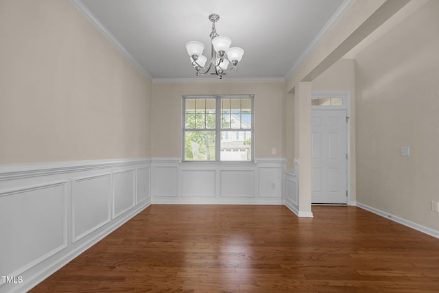 unfurnished dining area featuring crown molding, wainscoting, wood finished floors, and a chandelier