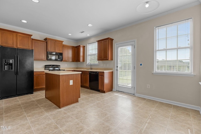 kitchen featuring crown molding, light countertops, brown cabinetry, a center island, and black appliances