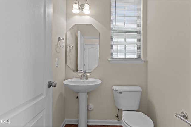 bathroom featuring toilet, baseboards, and a sink