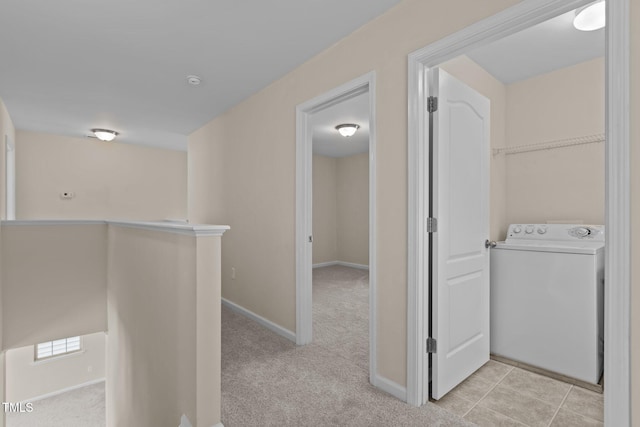 hall featuring baseboards, washer / clothes dryer, and light carpet