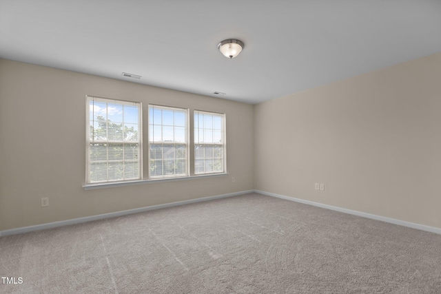 spare room featuring visible vents, carpet flooring, and baseboards