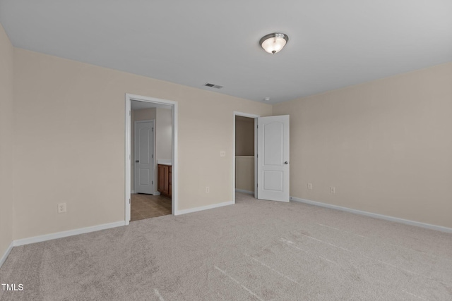 unfurnished bedroom featuring baseboards, visible vents, carpet, and ensuite bath