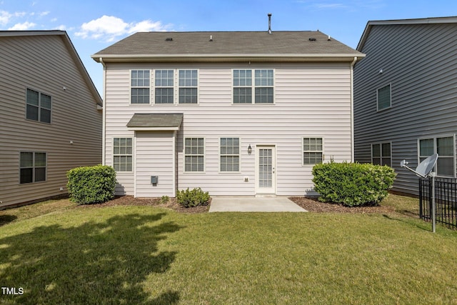 back of house featuring a lawn, a shingled roof, and a patio area