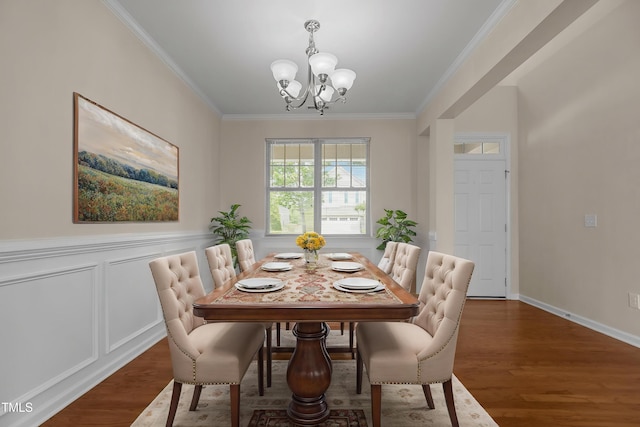 dining space with a chandelier, ornamental molding, wood finished floors, and a wainscoted wall