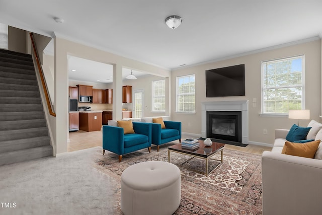 living area with crown molding, a fireplace with flush hearth, stairs, and baseboards