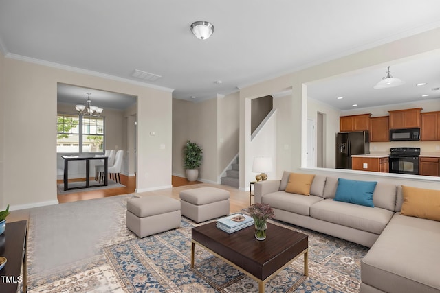 living room with an inviting chandelier, baseboards, visible vents, ornamental molding, and stairway