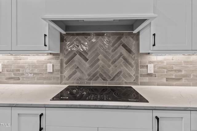 kitchen featuring decorative backsplash, custom range hood, white cabinets, and black electric cooktop