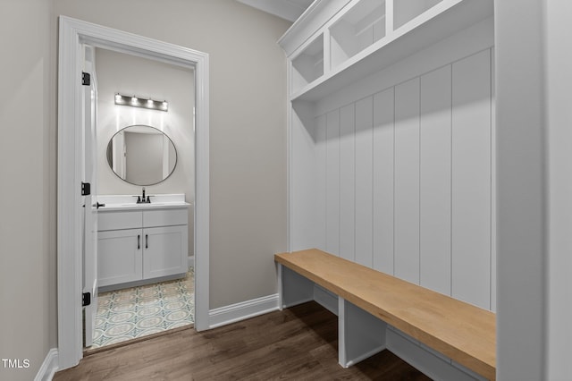 mudroom featuring baseboards, dark wood finished floors, and a sink