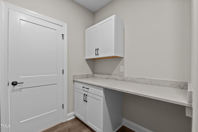 unfurnished office featuring dark wood-type flooring and baseboards