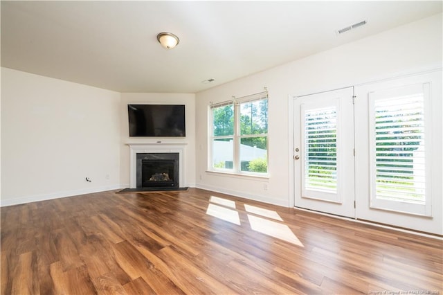 unfurnished living room featuring baseboards, visible vents, wood finished floors, and a fireplace