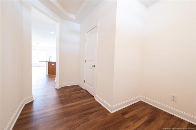 hallway featuring baseboards and dark wood-type flooring