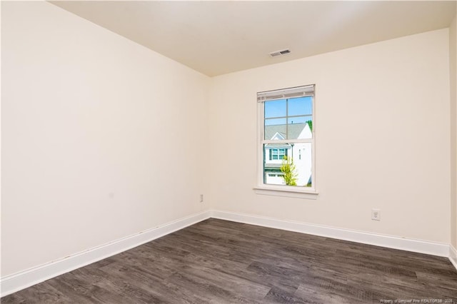 spare room featuring baseboards, visible vents, and dark wood-style floors
