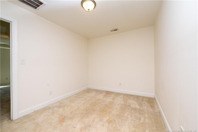 spare room with baseboards, light colored carpet, and visible vents