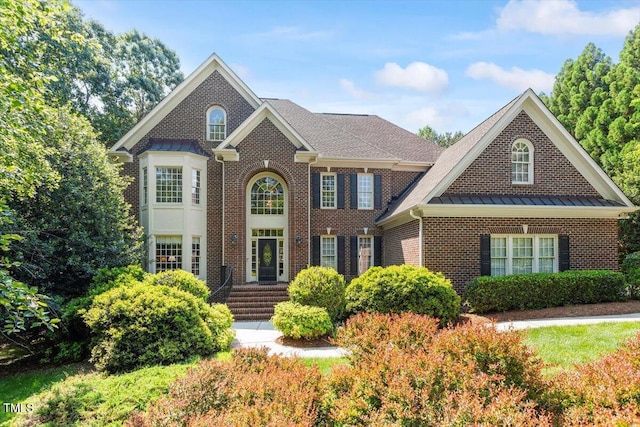 view of front of house featuring brick siding, a standing seam roof, and metal roof
