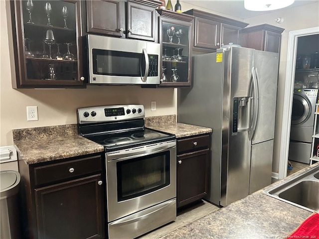 kitchen featuring separate washer and dryer, glass insert cabinets, a sink, and stainless steel appliances