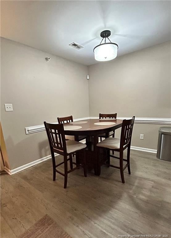 dining area with baseboards, visible vents, and wood finished floors
