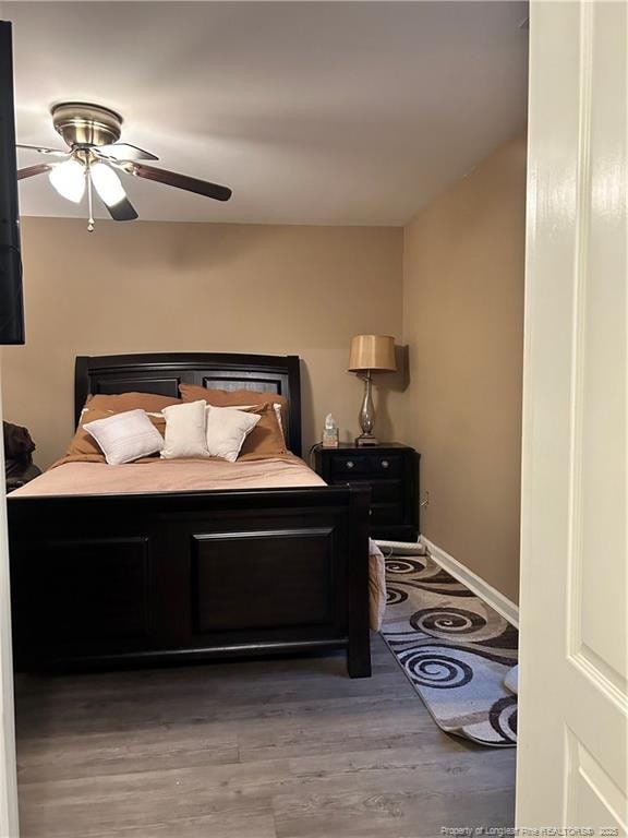 bedroom featuring baseboards, a ceiling fan, and wood finished floors