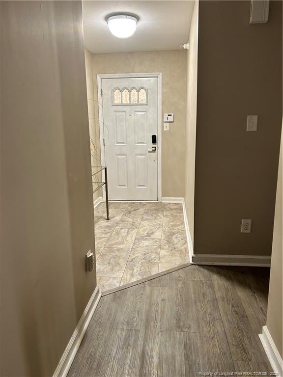 doorway with baseboards and wood finished floors