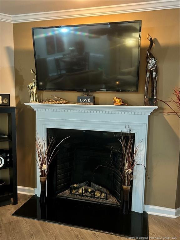interior details featuring crown molding, baseboards, a fireplace, and wood finished floors