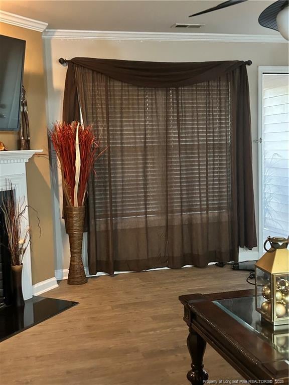 interior space with baseboards, ornamental molding, wood finished floors, and visible vents