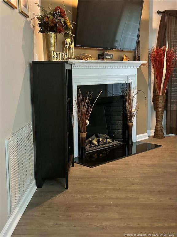 interior details with baseboards, visible vents, wood finished floors, and a fireplace