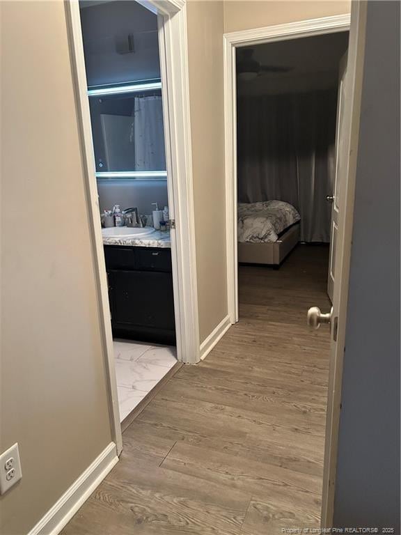 hall with baseboards, a sink, and wood finished floors