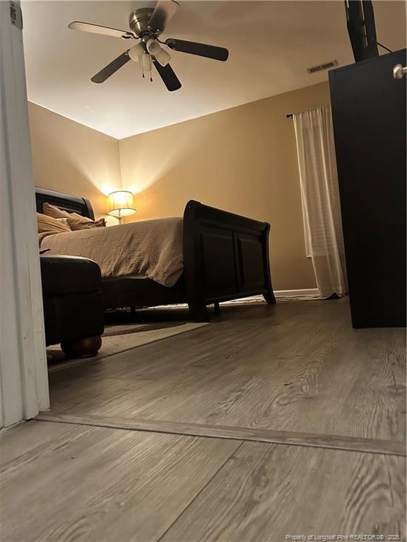 bedroom with ceiling fan, wood finished floors, and visible vents