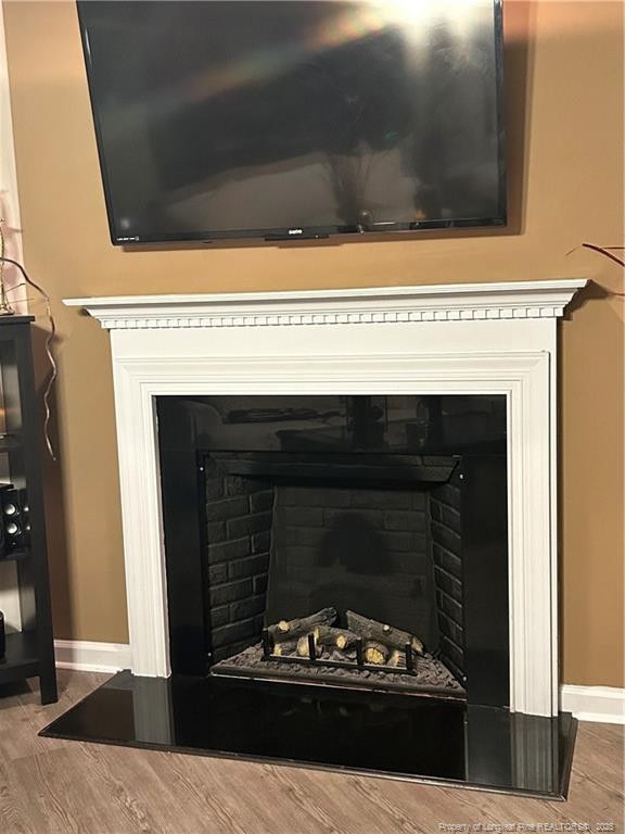 details with baseboards, wood finished floors, and a fireplace