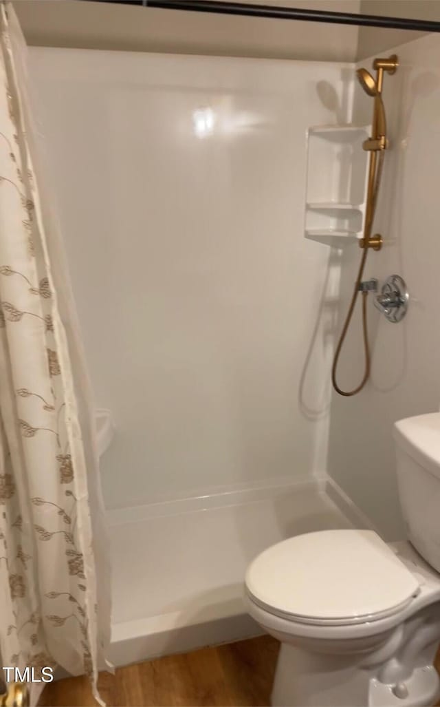 bathroom with wood finished floors, a stall shower, and toilet