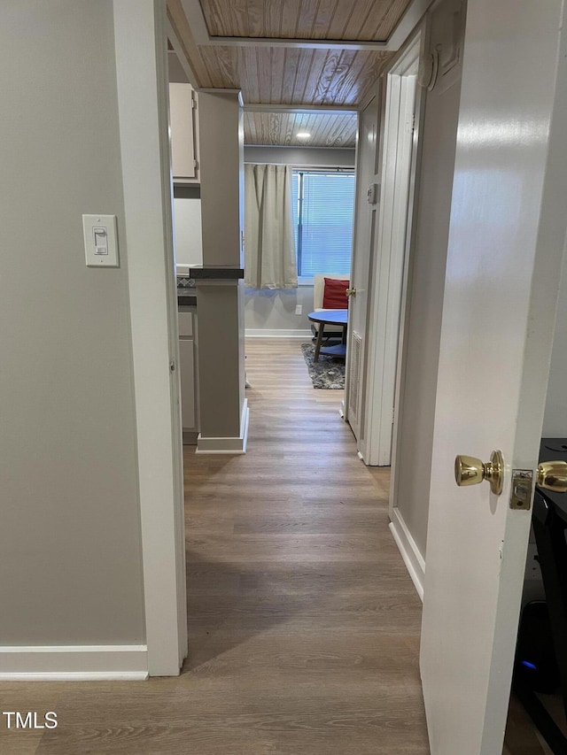 hall with baseboards, wood finished floors, and wooden ceiling