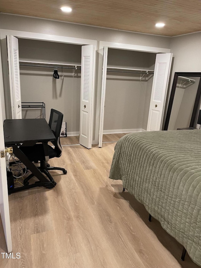 bedroom with recessed lighting, light wood finished floors, and two closets