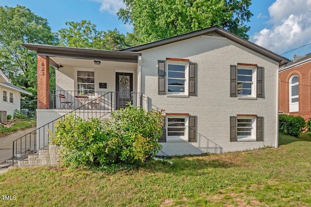 bungalow-style home with brick siding, stairs, and a front lawn