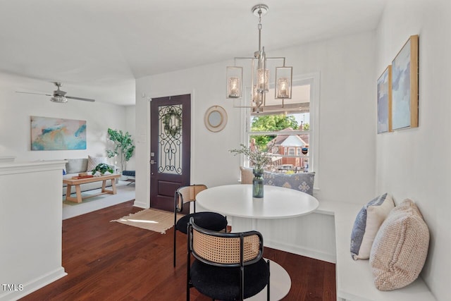 dining space with baseboards, ceiling fan with notable chandelier, and dark wood finished floors