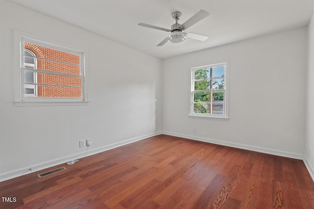 empty room with ceiling fan, baseboards, visible vents, and wood finished floors