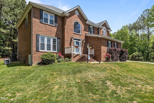 traditional-style house with a front lawn, brick siding, fence, and central air condition unit