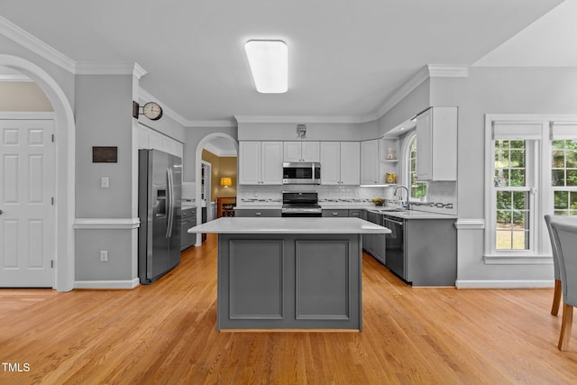 kitchen with stainless steel appliances, tasteful backsplash, light countertops, and white cabinets