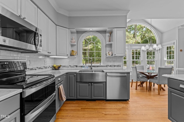 kitchen featuring a sink, open shelves, stainless steel appliances, gray cabinets, and light wood-style floors