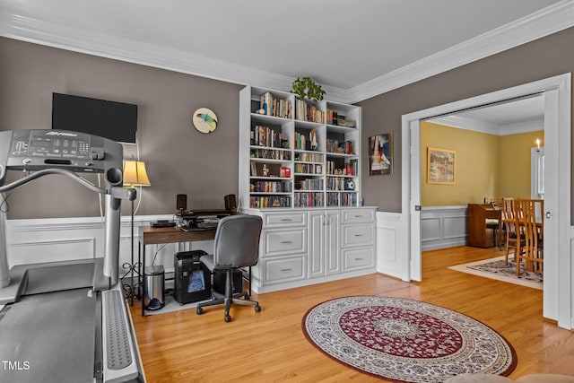 office with a decorative wall, wainscoting, crown molding, and wood finished floors