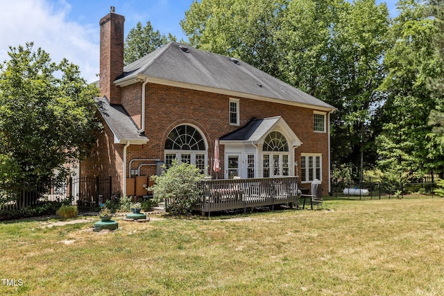 rear view of house featuring a chimney, a lawn, brick siding, fence, and a wooden deck