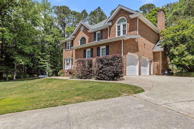 view of front of property featuring an attached garage, a chimney, a front yard, brick siding, and driveway