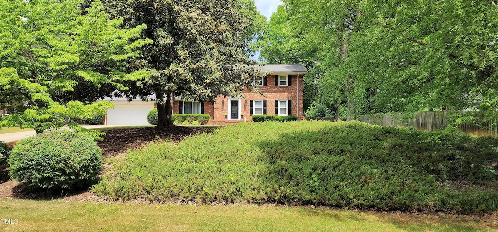 view of front of property featuring concrete driveway, brick siding, and fence