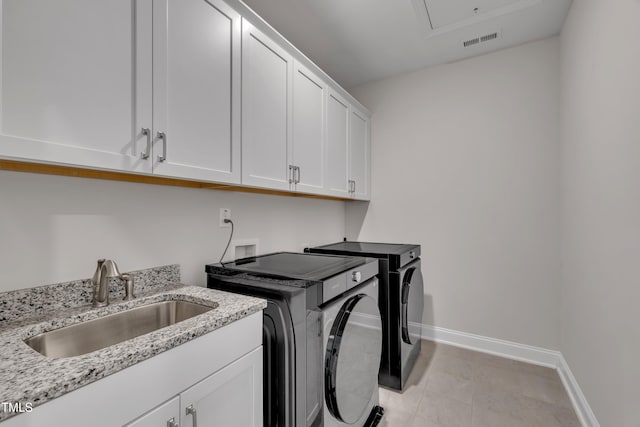 laundry area with cabinet space, washing machine and clothes dryer, a sink, baseboards, and visible vents